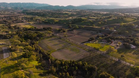 Aerial-Footage-of-Quaint-Countryside-in-Santa-Ynez-California,-Cars-on-Road-Surrounded-by-Vineyards-and-Fields