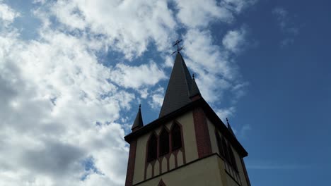 Torre-De-La-Iglesia-Con-Una-Cruz-Encima-Sobre-Un-Fondo-De-Cielo-Azul-Y-Nubes-Ondulantes