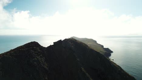 Aerial-Shot-of-People-on-the-top-of-the-Mountain-surrounded-by-the-Ocean