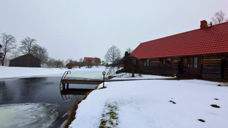Dolly-Nach-Vorn,-Filmische-Ansicht-Eines-Lettischen-Ferienhauses-Mitten-Im-Winter,-Tauwetter,-Natürlicher-Pool-Vorne