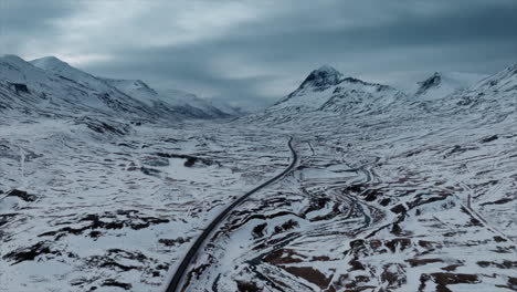 Drone-footage-over-Northern-Iceland,-showcasing-snowy-mountains-and-road-views,-capturing-the-serene-winter-landscape-from-above