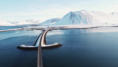 Paisaje-Aéreo-Temporada-De-Invierno-En-Islandia-Con-Puente-De-Carretera-Cubierto-De-Nieve-Blanca-Cruzando-La-Península-De-Snaefellness