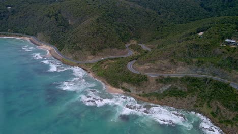 Drone-shot-of-coastal-winding-highway-bends-along-famous-Great-Ocean-Road-in-Victoria,-Australia