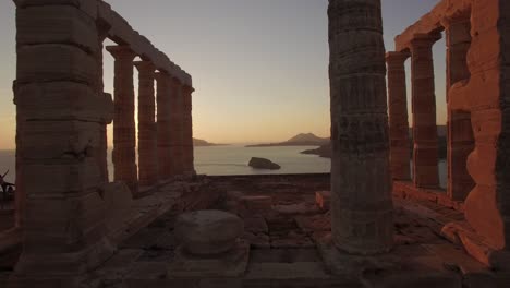 Epische-Drohnenaufnahmen-Des-Poseidon-Tempels-Bei-Sonnenuntergang-Zur-Goldenen-Stunde,-Touristengebiet