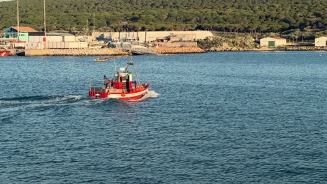 Ein-Boot-Gleitet-Anmutig-über-Die-Gewässer-Der-Spanischen-Küste,-Mit-Einem-Malerischen-Fischerdorf-Im-Hintergrund,-Das-Die-Zeitlose-Verbindung-Zwischen-Mensch-Und-Meer-Verkörpert