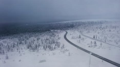 Drone-following-the-main-road-to-Inari,-gloomy-winter-day-in-Saariselka,-Finland