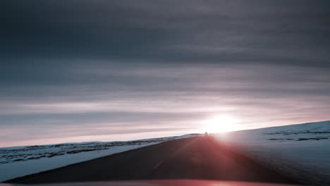 POV-driving-video-through-Northern-Iceland's-snowy-landscape-at-sunset,-capturing-serene-winter-beauty-and-soft-lighting