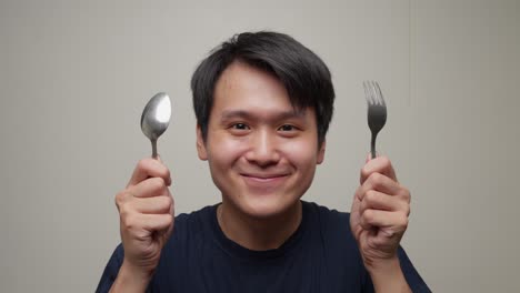 Closeup-shot-young-southeast-asian-man-gets-happy-lifting-fork-spoon-for-eating-portrait-studio-shot