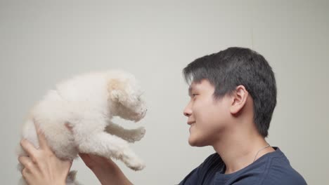 Portrait-southeast-asian-young-male-hugging-pet-toy-poodle-white-cute-dog-happiness-expression-of-friendship,-inside-indoors-shot