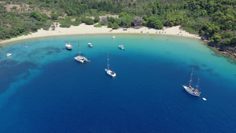 Aéreo:-Toma-Panorámica-Con-Drones-De-La-Playa-De-La-Isla-Tsougria-Cerca-De-Skiathos,-Esporadas,-Grecia-Con-Veleros-Y-Catamaranes-Amarrados