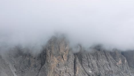 Aerial-zoom-out-footage-of-the-rocky-mountains-above-Passo-Gardena-covered-completely-in-clouds