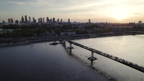 Gente-Caminando-Por-El-Puente-Agrafka-Sobre-Vístula-Con-Vistas-A-La-Ciudad-Al-Atardecer-En-Varsovia,-Polonia