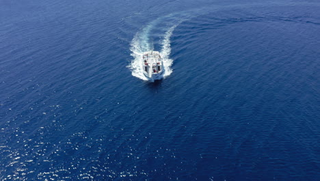 Aerial:-Following-a-tourist-boat-moving-quickly-across-the-blue-sea