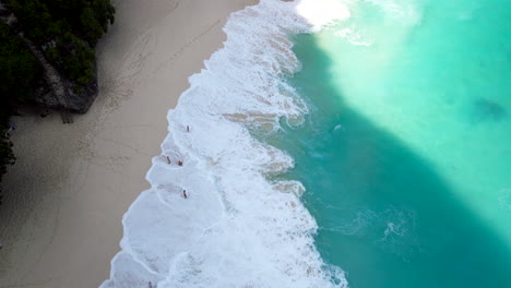 Tourists-enjoying-white-sandy-beach-and-incoming-ocean-tide