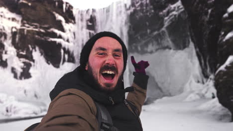 tourist-vlog-under-the-famous-landmark-in-Iceland-Skogafoss-waterfall,-during-winter-season