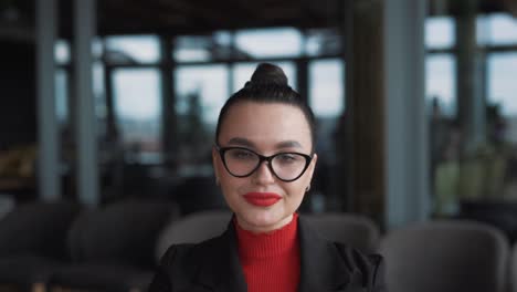 portrait-of-a-beautiful-young-woman-in-glasses-and-braces,-a-freelancer,-sits-in-a-stylish-restaurant-dressed-in-business-attire,-wearing-glasses-and-smiling