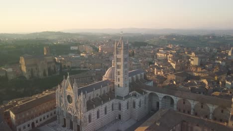 Aerial-of-Duomo-of-Siena-old-ancient-historical-cathedral-drone-approaching-medieval-town-in-Tuscany-Italy