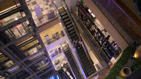 People-going-up-and-down-a-shopping-mall-using-the-escalators-and-elevators-inside-a-shopping-mall-in-Bangkok,-Thailand