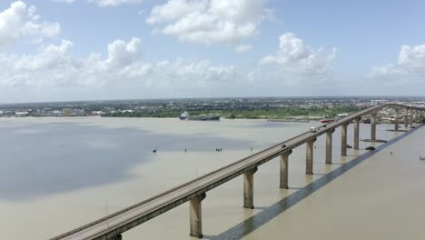 Wide-angle-aerial-shot-of-Jules-Wijdenbosch-Bridge-between-Paramaribo-and-Meerzorg-in-Suriname,-South-America,-with-traffic-as-drone-flies-and-orbits-over-bridge