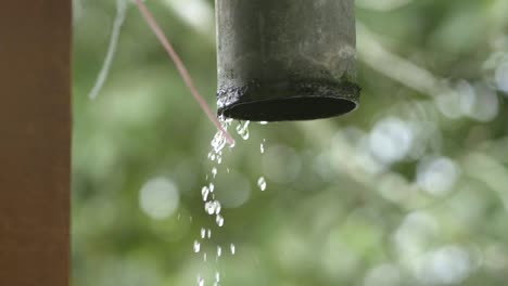 Rainwater-pouring-out-of-rain-gutter-from-roof,-raindrops-out-of-PVC-pipe