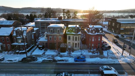 Casas-Victorianas-Cubiertas-De-Nieve-Al-Atardecer-Con-Un-Telón-De-Fondo-De-Colinas-Y-Un-Río