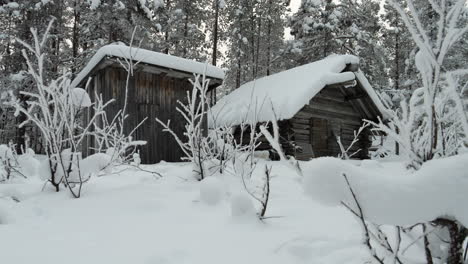 Small-Wooden-Cabin-in-Lapland-Winter-Forest,-Snow-in-Foreground-PAN