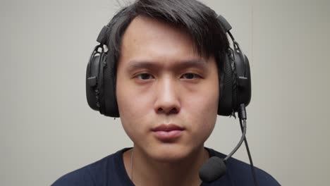 Music-studio-Chinese-man-producer-puts-headphones-on-and-smiles-listening-waving-shaking-his-head,-closeup-portrait-face-shot