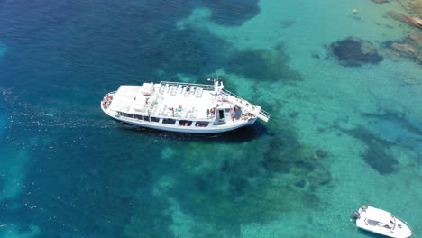 Aerial:-A-cruise-boat-moving-slowly-towards-Tsougria-island-beach-near-Skiathos-with-turquoise-clear-blue-water