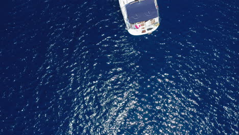 Aéreo:-De-Arriba-Hacia-Abajo-Revela-Una-Toma-De-Un-Velero-Amarrado-En-El-Mar-Azul-Con-Un-Dron