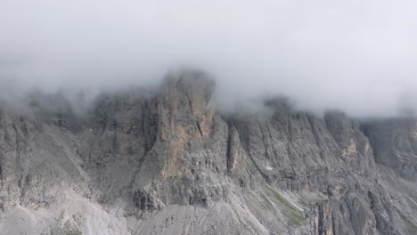 Aerial-drone-footage-captures-the-rugged-peaks-of-Passo-Gardena-enveloped-in-clouds-as-the-drone-ascends-and-turns-to-the-right