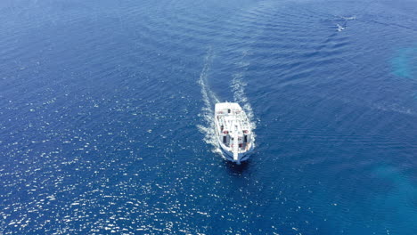 Aerial:-Following-a-tourist-boat-moving-slowly-on-turquoise-clear-blue-water