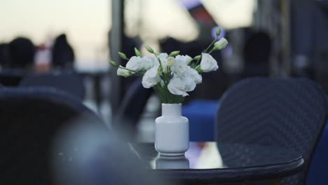 Elegant-outdoor-restaurant-furniture-decorated-with-a-white-ceramic-vase-with-roses
