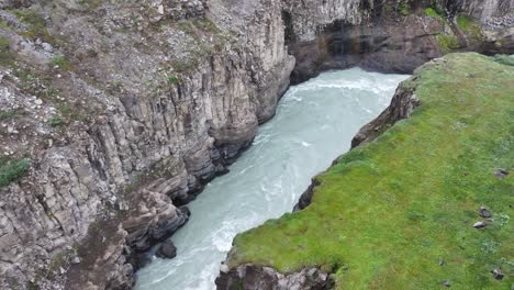 Aerial-View,-Glacial-River-Canyon,-Cliffs-and-Green-Grass,-Landscape-of-Iceland