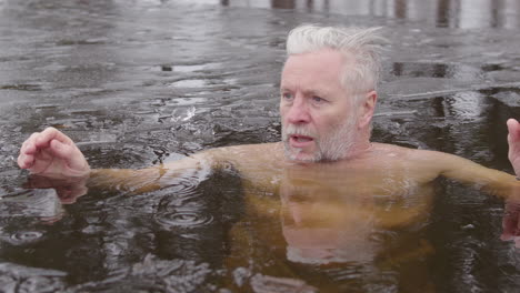 Closeup-slomo-shot-of-a-man-dipping-his-head-under-the-icy-lakewater,-Sweden