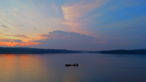 Morning-calm-lake-a-boat-is-flowing-the-surfaces-,-cloudy-morning-and-lake-reflecting-the-atmospheric-effects-of-the-sky