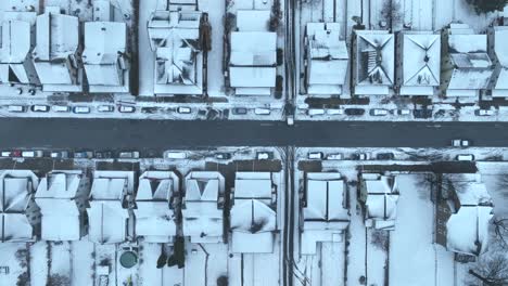 Top-down-aerial-of-snow-covered-town-houses-and-street