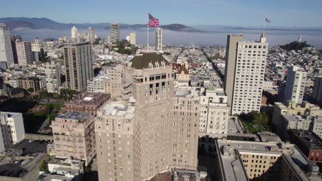 Drone-Shot-of-American-Flag-Waving-on-InterContinental-Mark-Hopkins-Hotel,-Nob-Hill,-San-Francisco-CA-USA