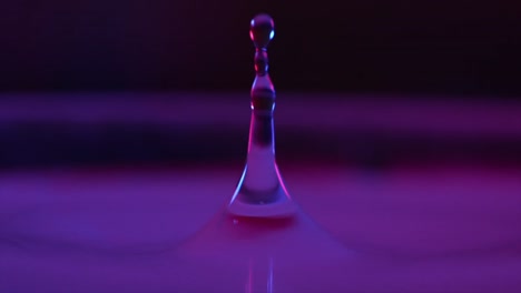 dripping-water-drop-falling-in-water,-macro-close-view,-slowmotion-cinema-camera,-1000fps,-purple-background