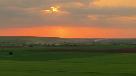Aerial-shot-showing-green-agricultural-fields-in-the-light-of-a-orange-sunset,-HDR