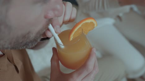 Slow-motion-over-the-shoulder-shot-of-a-man-drinking-a-orange-drink