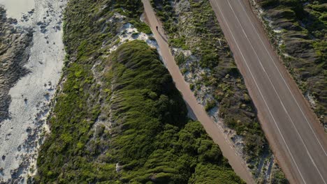 Cyclist-racing-along-cycle-path-on-cliff-between-beach-and-road