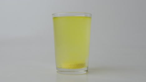 Glass-of-water-with-an-effervescent-vitamin-C-tablet,-white-background
