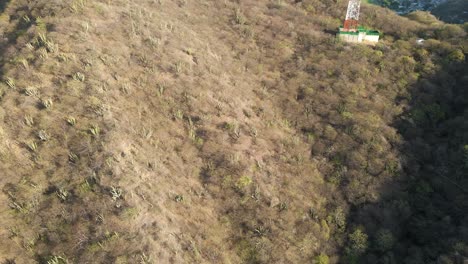 Bird's-Eye-drone-shot-pans-upwards-across-the-arid-mountains-to-reveal-the-cityscape-of-Santa-Marta,-Colombia