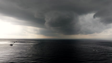 Dramatic-stormy-cumulus-clouds-with-boat-navigating-over-dark-sea