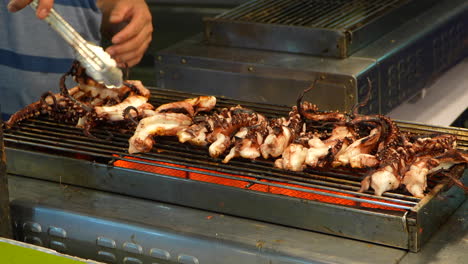 Person-grilling-squids-pieces-in-street-market