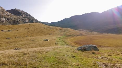 Lone-Male-Hiker-Walking-Across-Wild-Meadow-Valley-In-Valmalenco-alps