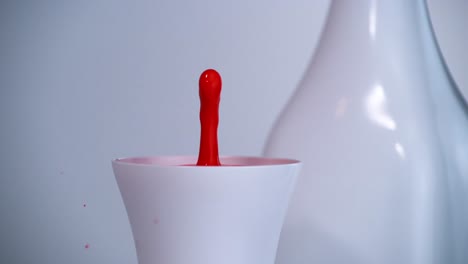 Red-drop-slowly-falls-into-a-white-cup