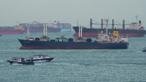 Large-cargo-ships-on-the-strait-of-Singapore,-boats-from-the-government-authority-sailing-around,-inspecting-the-custom-goods-and-documenting-it-before-it-arrives-to-inland