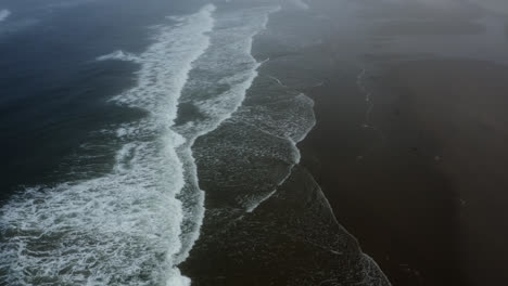 Wide-angle-flyover-above-Pacific-Ocean-waves-breaking-on-Oregon-Coast-beach