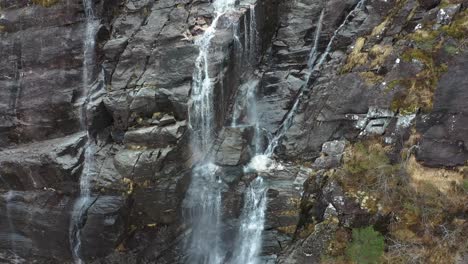 Water-stream-falling-to-sea-from-steep-cliff-in-Modalen-Norway,-tilt-up-bottom-to-top